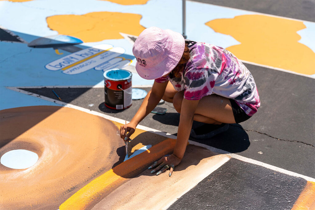 Woman painting a mural | Crenshaw Imperial Plaza